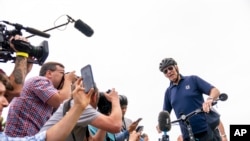 El presidente Joe Biden habla con los miembros de los medios de comunicación mientras da un paseo en bicicleta en el Parque Estatal Gordons Pond en Rehoboth Beach, Delaware, el 10 de julio de 2022.