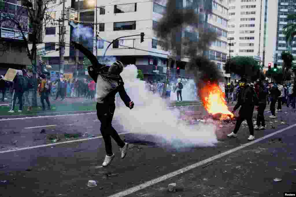 Un manifestante lanza una bomba lacrimógena disparada por personal de seguridad.
