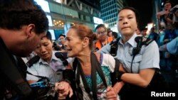 ARCHIVO - La policía detiene a la fotógrafa Paula Bronstein durante un enfrentamiento entre la policía y los manifestantes a favor de la democracia en el distrito comercial de Mongkok en Hong Kong en octubre de 2014. 