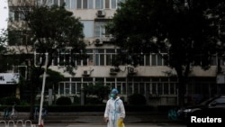 Un trabajador médico con traje protector cruza una calle tras un brote de la enfermedad del nuevo coronavirus en Beijing, el 6 de julio de 2022.