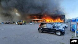 Esta fotografía tomada y publicada por el Servicio Estatal de Emergencias de Ucrania el 27 de junio de 2022 muestra a los bomberos apagando el fuego en un centro comercial afectado por un ataque con misiles rusos en Kremenchuk, que mató al menos a dos personas e hirió a decenas más.