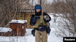 ARCHIVO - El fotógrafo ucraniano Maksim Levin lleva un gato cerca de la línea de separación de los separatistas respaldados por Rusia en la región de Donetsk, Ucrania, el 25 de enero de 2022.