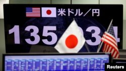 ARCHIVO: Un monitor que muestra el tipo de cambio del yen japonés frente al dólar estadounidense se ve a través de las banderas nacionales de EEUU y Japón en la empresa de comercio de divisas Gaitame.com en Tokio, Japón, el 13 de junio de 2022 REUTERS/Issei Kato/Foto de archivo