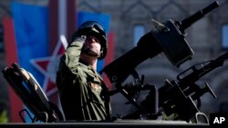 Un soldado ruso saluda durante el desfile del Día de la Victoria en Moscú. Putin dice haber ordenado el retiro de tropas cercanas a la frontera con Ucrania.