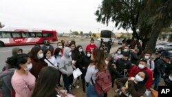 Migrantes escuchan a un voluntario en un estacionamiento después de ser detenidos y procesados ​​para solicitar asilo por parte de Estados Unidos. autoridades, viernes 12 de abril de 2024, en San Diego. (Foto AP/Gregory Bull)