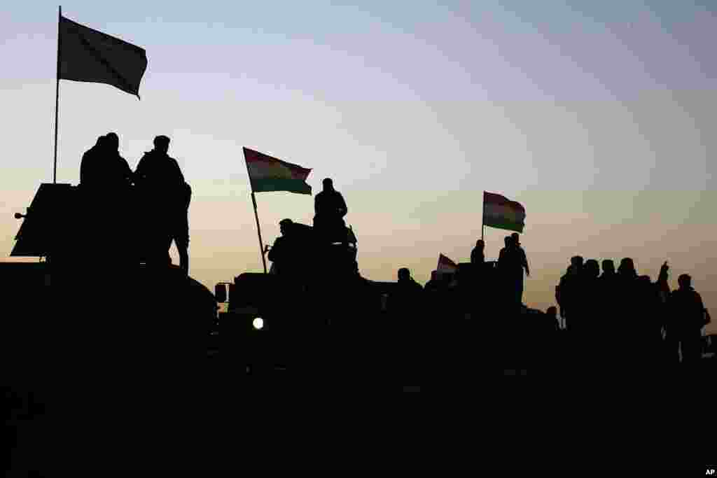 Para pejuang Peshmerga Kurdi berdiri di atas kendaraan militer saat bergerak maju ke arah desa-desa yang mengelilingi Mosul, di Khazer, Irak (17/10). (AP/Bram Janssen)