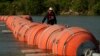 Una persona en kayak pasa al lado de boyas instaladas como barrera en el Río Grande, el 1 de agosto de 2023, en Eagle Pass, Texas, EEUU.