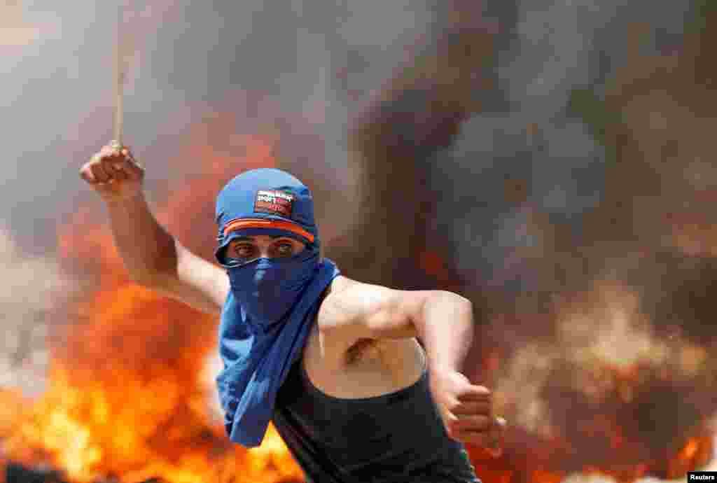 A Palestinian demonstrator uses a sling to hurl stones at Israeli troops during a protest against Jewish settlements and Israel&#39;s plan to annex parts of the occupied West Bank, near Ramallah.