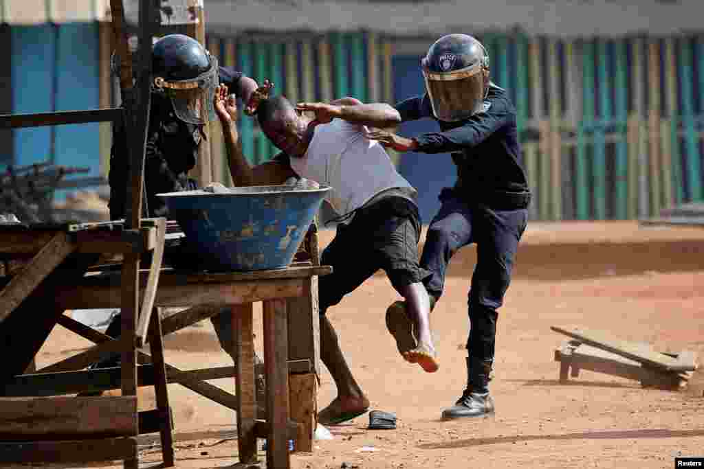 Policemen detain a demonstrator during a protest against President Alassane Ouattara's decision to stand for a third term, in Abidjan, Ivory Coast.
