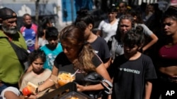 ARCHIVO: Personas reciben comidas calientes gratuitas en un comedor comunitario dirigido por el Movimiento de Trabajadores Excluidos (MTE) en Buenos Aires, Argentina, el viernes 8 de marzo de 2024.