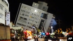 Rescuers are seen entering a building that collapsed onto its side from an early morning 6.4 magnitude earthquake in Hualien County, eastern Taiwan, Feb. 7 2018. Rescue workers are searching for any survivors trapped inside the building. 