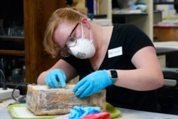 FILE - Conservator for the Virginia Department of Historic Resources, Chelsea Blake, works to open a time capsule that was removed from the pedestal that once held the statue of Confederate General Robert E. Lee, in Richmond, Va., Dec. 22, 2021.