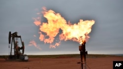 FILE - A flare burns natural gas at an oil well Aug. 26, 2021, in Watford City, N.D.