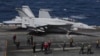 Un F-18 Super Hornet de la Marina de EEUU y miembros de la tripulación se ven en la cubierta de vuelo del USS Nimitz frente a la costa de Busan, Corea del Sur, el lunes 27 de marzo de 2023.