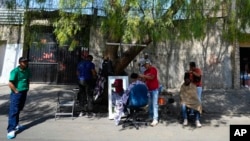 Migrantes venezolanos se cortan el pelo junto a las vías del tren bordeadas por tiendas de campaña improvisadas en la Ciudad de México, el martes 26 de marzo de 2024. 
