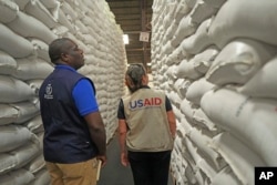 ARCHIVO - Funcionarios de USAID y PMA inspeccionan una donación de ayuda alimentaria por valor de 11 millones de dólares en Harare, Zimbabwe, el 17 de enero de 2024.