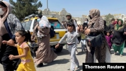 Mujeres con sus hijos intentan entrar en el aeropuerto internacional Hamid Karzai de Kabul, lunes 16 de agosto de 2021.