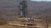 FILE - A group of journalists walk down a road in front of North Korea's Unha-3 rocket at the Sohae Satellite Station in Tongchang-ri, North Korea, April 8, 2012.