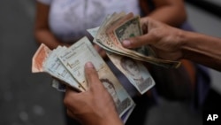ARCHIVO - Un trabajador del servicio de transporte de Caracas cuenta bolívares y dólares estadounidenses, el 9 de agosto de 2023.