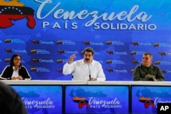 El presidente de Venezuela, Nicolás Maduro, en el centro, habla, mientras lo acompaña el vicepresidente venezolano, Delcy Rodríguez, a la izquierda, y el ministro de Defensa, Vladimir Padrino, a la derecha, durante una reunión con ciudadanos colombianos que residen en Venezuela. Caracas, 26 de septiembre de 2018. Foto de la oficina de prensa del Palacio de Miraflores via AP.