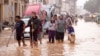 Warga berjalan melewati jalanan yang tergenang banjir di Valencia, Spanyol, pada 30 Oktober 2024. (Foto: AP/Alberto Saiz)
