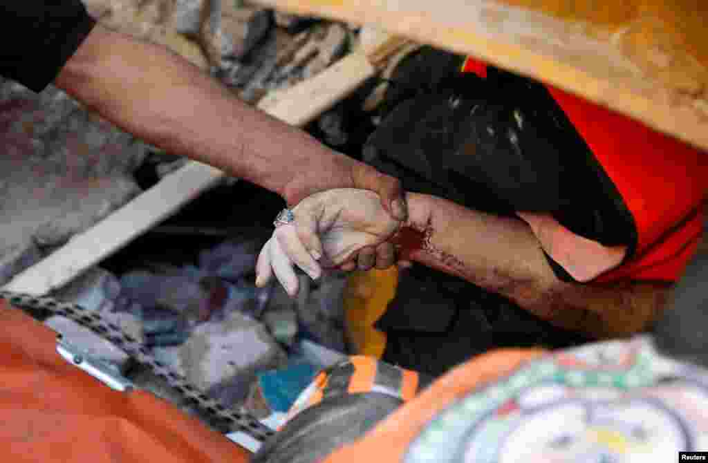 Un rescatista sostiene la mano de una v&#237;ctima entre los escombros en el lugar de los ataques a&#233;reos israel&#237;es, en la ciudad de Gaza.
