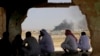 FILE - Jordanian residents of Jabir village watch aid deliveries to Syrians fleeing government offensives in the south as smoke from an unknown fire rises, July 3, 2018. 