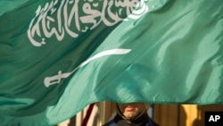 FILE - An embassy honor guard member is covered by the flag of Saudi Arabia, in Washington, March 22, 2018. The kingdom, on Feb 27, 2024, executed seven individuals for "creating and financing terrorist organizations and entities," its interior ministry said.