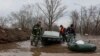 Emergency workers push their boats in a flooded area in Orenburg, Russia, Wednesday, April 10, 2024. Russian officials are scrambling to help homeowners displaced by floods, as water levels have risen in the Ural River. 