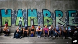 Manifestantes antigubernamentales descansan bajo un puente y un letrero que denuncia el hambre en Venezuela, en julio de 2017.