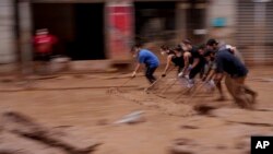 FILE - People clear mud from a street in an area affected by floods in Catarroja, Spain, Nov. 4, 2024. The October 29 disaster marked the country's deadliest floods in decades. A total of 224 people were killed nationwide, with 216 of them in Valencia.