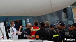 Agentes de la ley vigilan a los migrantes que llegan a Costa Rica en un vuelo de deportación desde Estados Unidos antes de ser enviados a sus países de origen, en el Aeropuerto Internacional Juan Santamaría, en Alajuela, Costa Rica, el 20 de febrero de 2025.