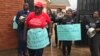 A group of men and women carry placards to confront the Uganda police at police headquarters as they protest the kidnapping and murder of women, June 5, 2018. 