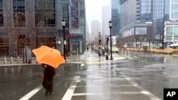 ARCHIVO - Una persona se prepara para protegerse del viento mientras cae una mezcla invernal de nieve y lluvia en Boston, el 14 de marzo de 2023. Se espera que un sistema climático invernal que se mueve a través de EEUU azote la costa este este fin de semana.