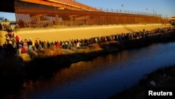 Migrantes hacen cola cerca del muro fronterizo después de cruzar el río Bravo para entregarse a los agentes de la Patrulla Fronteriza de EEUU para solicitar asilo en El Paso, Texas, visto desde Ciudad Juárez, México, el 14 de diciembre de 2022. REUTERS/José Luis González