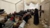 FILE - Displaced people gather inside a tent in the al-Hol camp in northeastern Syria, Dec. 8, 2018. 