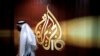 ARCHIVO: Un empleado de la cadena de televisión qatarí Al Jazeera camina frente al logo del canal en Doha, Qatar.