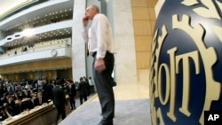 FILE - An ILO, International Labor Organization, staff member gestures next to a sign showing the ILO logo in Geneva, Switzerland.