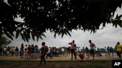 Venezolanos se encuentran junto al río Arauca, la frontera natural entre Venezuela y Colombia, luego de cruzar en bote en Arauquita, Colombia, el viernes 26 de marzo de 2021.