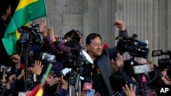 El presidente boliviano Luis Arce levanta un puño cerrado rodeado de partidarios y medios de comunicación frente al palacio de gobierno en La Paz, Bolivia, el miércoles 26 de junio de 2024. 
