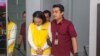 Petugas imigrasi mengawal Yusuke Yamazaki, kiri, buronan asal Jepang yang dicari karena kasus penipuan di negara asalnya, sebelum dideportasi di Batam, Selasa, 12 Maret 2024. (Foto: AP)