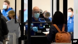 Un agente de la Administración de Seguridad en el Transporte (TSA) ayuda a un viajero en un punto de seguridad en el aeropuerto Love Field, en Dallas, Texas, el 24 de noviembre de 2020.