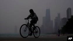 Un ciclista avanza por la ribera del lago Michigan en Chicago bajo una bruma causada por los incendios forestales en Canadá el 27 de junio de 2023.