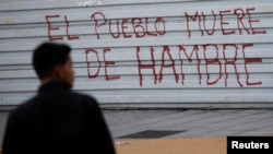 Un hombre pasa frente a un grafitis en protesta contra el hambre, en Caracas, Venezuela, agosto de 2018. Archivo.