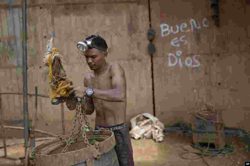 Un trabajador sujeta un gran cubo a un sistema de poleas para subir piedras por un pozo en una mina subterránea de oro en El Callao, estado Bolívar, en Venezuela, el viernes 28 de abril de 2023. Los cubos también son utilizados para subir y bajar herramientas en el lugar.&nbsp;