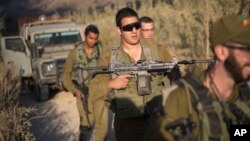 FILE - Israeli soldiers secure a road leading to where projectiles fired from Syria hit the Israeli-controlled part of the Golan Heights, near Majdal Shams, Sept. 13, 2016. 