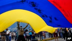 Partidarios de Tomás Guanipa, quien fuera candidato a alcalde de la Mesa de Unidad Democrática (MUD), ondean una bandera venezolana en un mitin el primer día de la campaña, en Caracas, el 28 de octubre de 2021. Foto: AP.