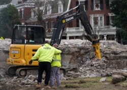 Workers react after the 1887 time capsule was removed from the former Robert E. Lee monument in Richmond, Virginia, Dec. 27, 2021.