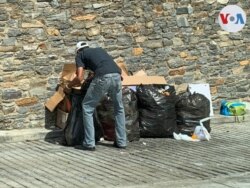 Un hombre busca comida en bolsas de basura ubicadas en las inmediaciones de edificios en una zona acomodada del este de Caracas. Agosto, 2021. Foto: Carolina Alcalde - VOA.