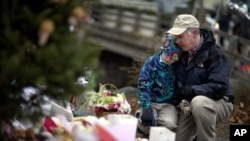 December 16: David Freedman, right, kneels with his son Zachary, 9, as they visit a sidewalk memorial for the 26 people, including 20 children, who were killed at Sandy Hook Elementary School in Newtown, Connecticut.
